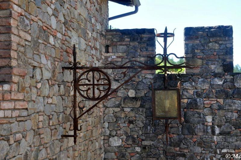 Castello Di Amorosa: кованый фонарь у каменной стены